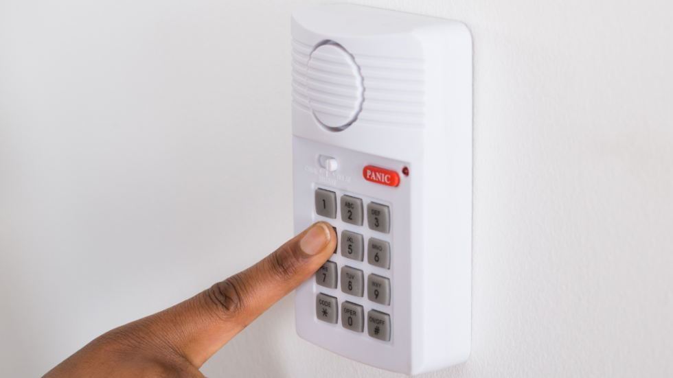 Person's finger pressing a button on a security system.
